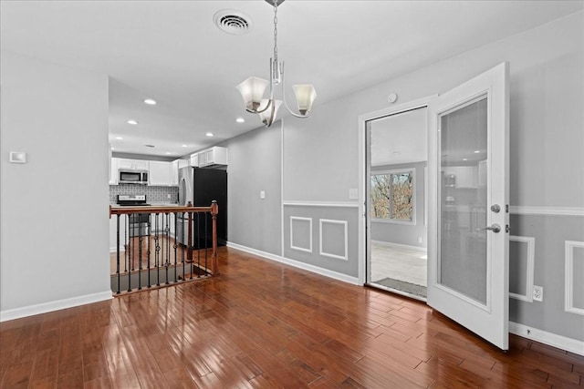 interior space with a chandelier, dark wood-style flooring, visible vents, and baseboards