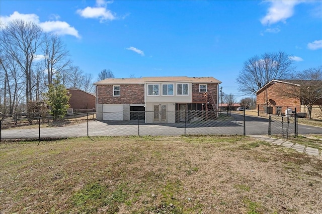 back of property with a yard, stairway, an attached garage, fence, and driveway