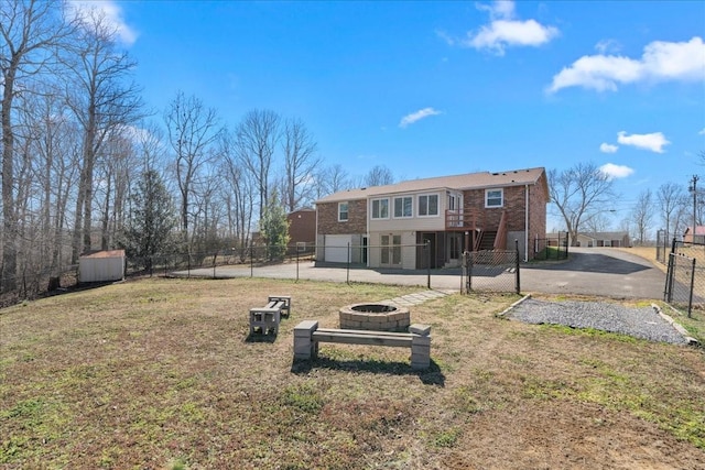 exterior space with an outbuilding, brick siding, a lawn, an outdoor fire pit, and fence private yard