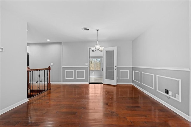 empty room featuring visible vents, hardwood / wood-style flooring, a chandelier, a decorative wall, and recessed lighting