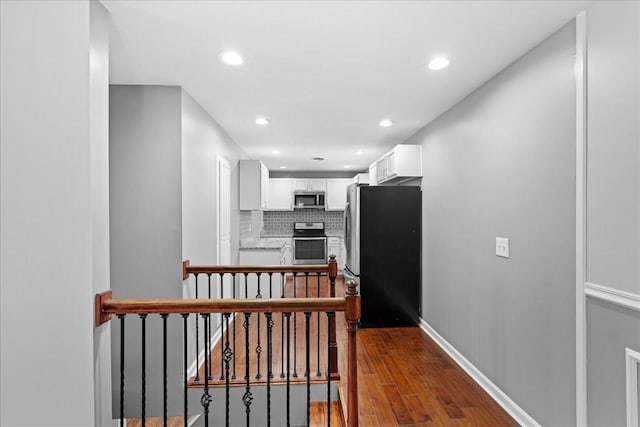 kitchen featuring backsplash, appliances with stainless steel finishes, dark wood-type flooring, white cabinetry, and baseboards