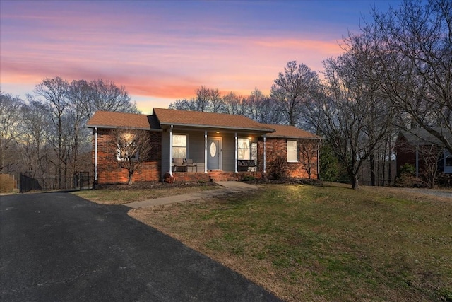 single story home with covered porch, a front lawn, and brick siding