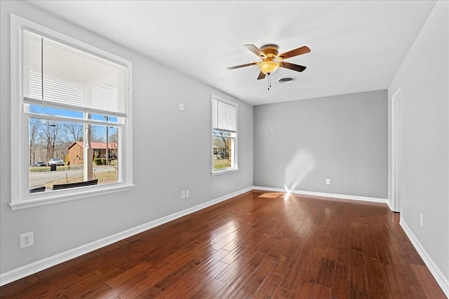 unfurnished room featuring baseboards, visible vents, and wood finished floors