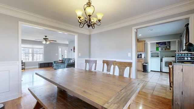 dining room with ceiling fan with notable chandelier, ornamental molding, wainscoting, and washer / dryer