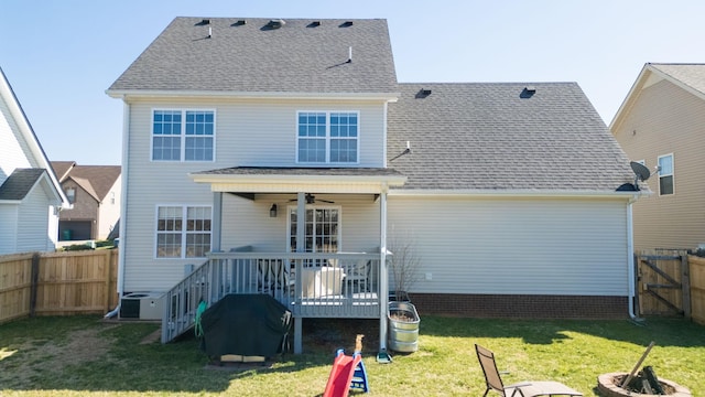 back of house featuring central air condition unit, a lawn, a ceiling fan, a deck, and a fenced backyard