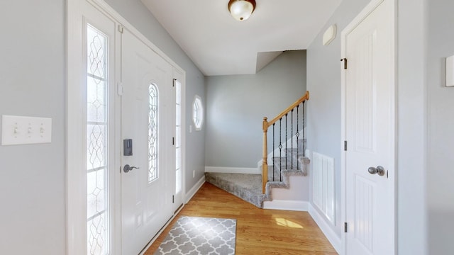 entryway featuring visible vents, light wood-style flooring, baseboards, and stairs