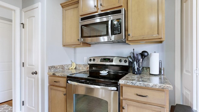 kitchen with stainless steel appliances, light brown cabinetry, and light stone countertops