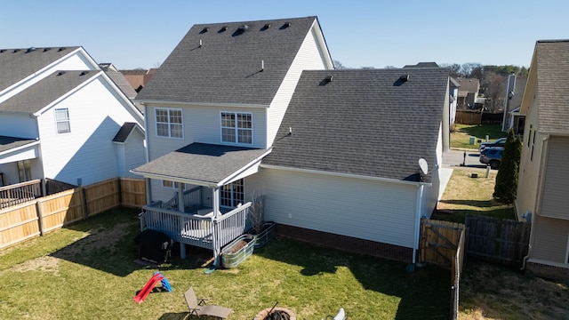 back of property featuring a shingled roof, a fenced backyard, and a lawn