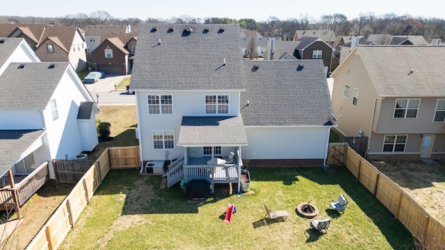 rear view of property featuring a residential view, a fenced backyard, a yard, and a fire pit