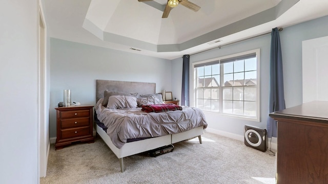 bedroom featuring visible vents, a tray ceiling, baseboards, and light colored carpet