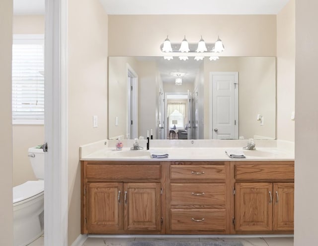 bathroom with double vanity, a sink, and toilet