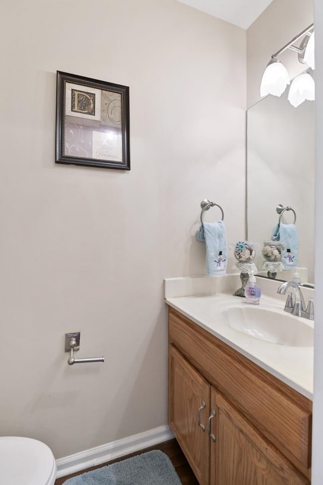 bathroom featuring toilet, vanity, and baseboards