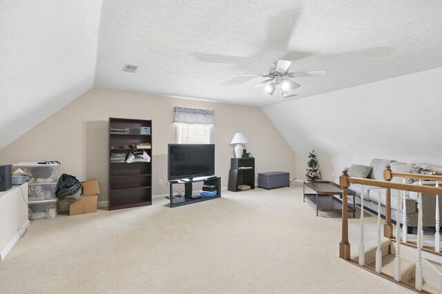 interior space with a textured ceiling, carpet, lofted ceiling, and a ceiling fan