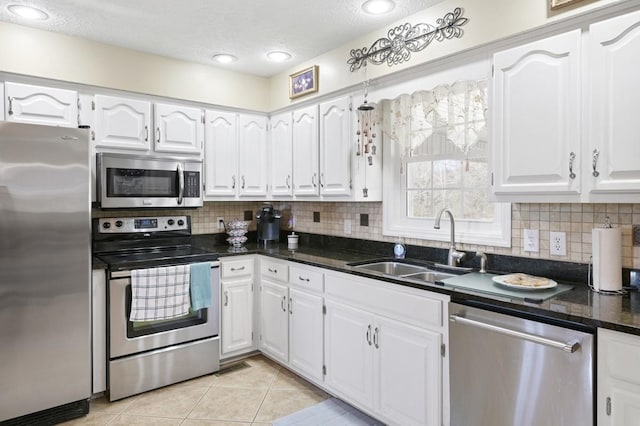 kitchen featuring light tile patterned floors, white cabinetry, appliances with stainless steel finishes, and a sink