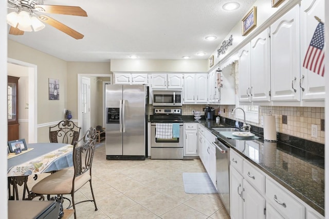 kitchen with white cabinets, a sink, stainless steel appliances, backsplash, and light tile patterned flooring