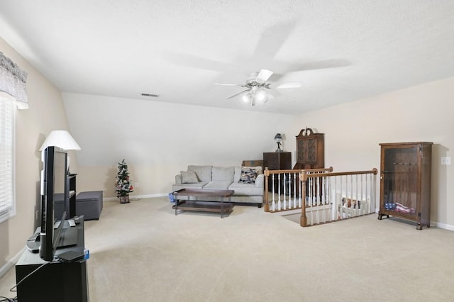 living area with baseboards, visible vents, a ceiling fan, and light colored carpet