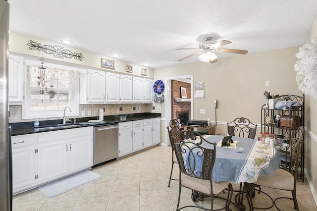 kitchen with light tile patterned floors, a sink, white cabinetry, dishwasher, and tasteful backsplash