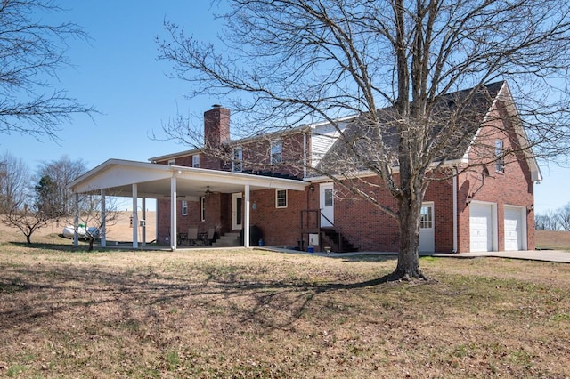 back of property featuring driveway, brick siding, a lawn, and a chimney