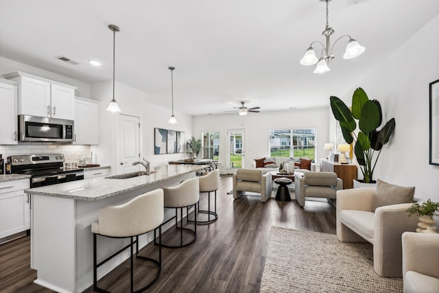 kitchen with a breakfast bar, decorative backsplash, appliances with stainless steel finishes, open floor plan, and a sink