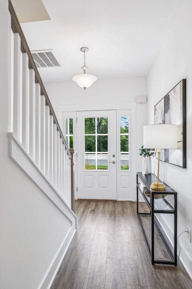 entryway with stairway, wood finished floors, visible vents, and baseboards