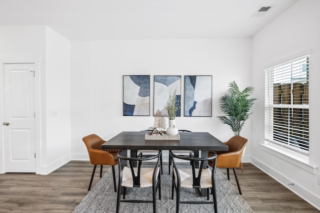 dining area with dark wood-type flooring, visible vents, and baseboards