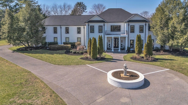 neoclassical / greek revival house featuring a front yard, french doors, roof with shingles, and stucco siding