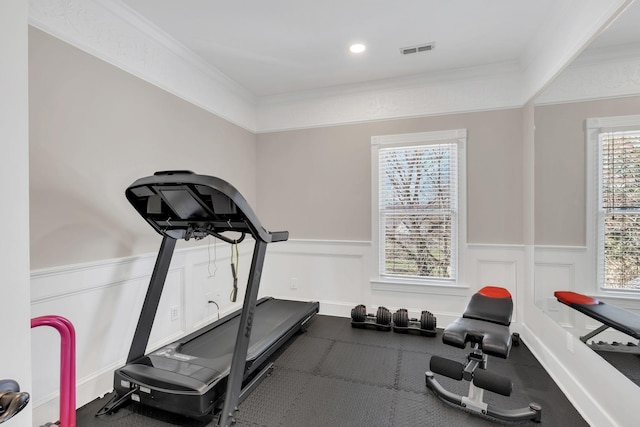 exercise room featuring a wainscoted wall, visible vents, and ornamental molding