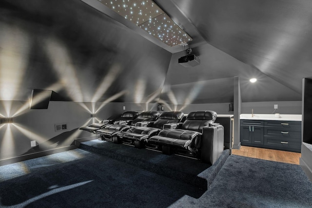 home theater room with vaulted ceiling, visible vents, and light wood-style floors