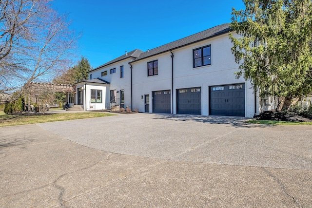 view of front of home featuring concrete driveway, brick siding, an attached garage, and a pergola