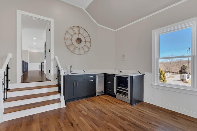 bar with wine cooler, wood finished floors, stairs, ornamental molding, and indoor wet bar