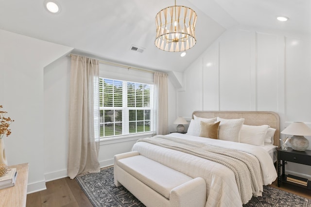 bedroom featuring lofted ceiling, wood finished floors, visible vents, baseboards, and an inviting chandelier