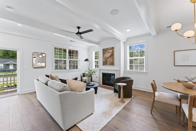 living area with a glass covered fireplace, beam ceiling, baseboards, and hardwood / wood-style floors