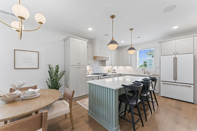 kitchen featuring light countertops, light wood-type flooring, custom range hood, and high quality appliances