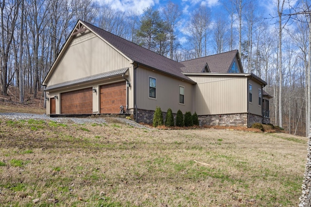 view of property exterior with a garage, stone siding, a yard, and driveway