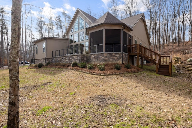 exterior space with stairs, roof with shingles, and a sunroom