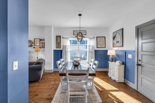 dining room featuring dark wood-type flooring, a chandelier, and baseboards