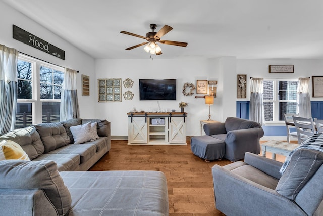 living area with a ceiling fan, a wealth of natural light, baseboards, and wood finished floors