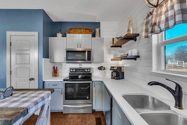 kitchen with open shelves, light countertops, appliances with stainless steel finishes, dark wood-type flooring, and a sink