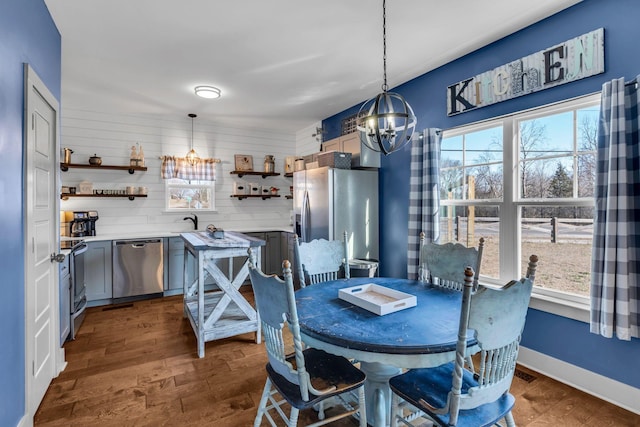 dining area with a wealth of natural light, dark wood-style flooring, a notable chandelier, and baseboards