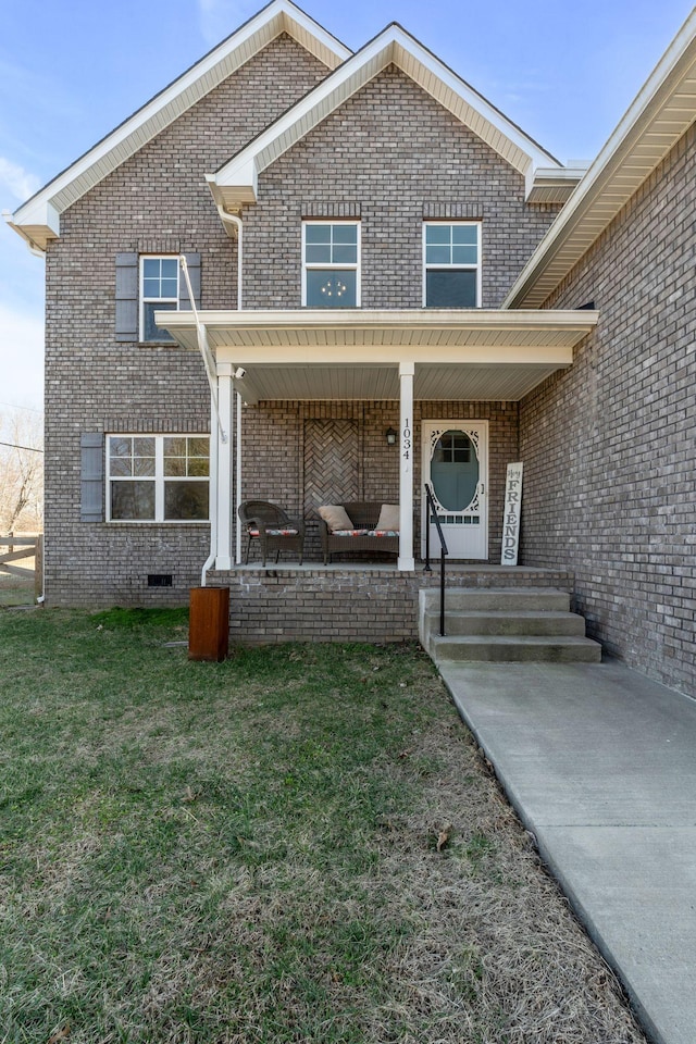 view of front of house featuring a porch, crawl space, a front yard, and brick siding