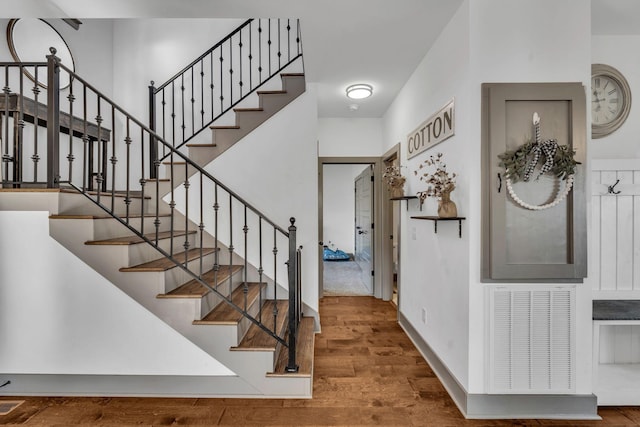 stairs featuring wood finished floors, visible vents, and baseboards