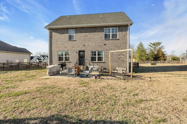 back of property with a patio area, a yard, a fenced backyard, and brick siding