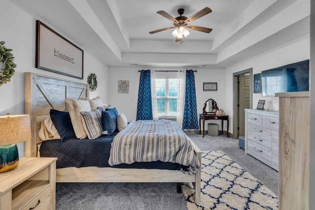 bedroom with light carpet, ceiling fan, a tray ceiling, and baseboards