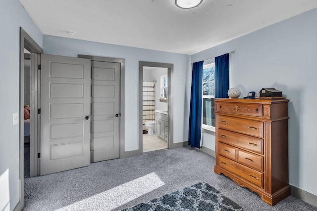 bedroom with light carpet, baseboards, and ensuite bathroom