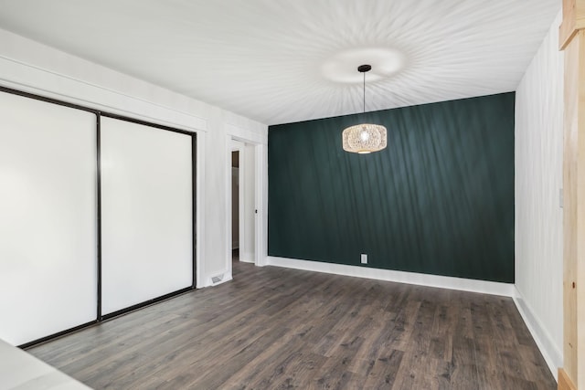 unfurnished bedroom featuring a chandelier, wood finished floors, visible vents, and baseboards