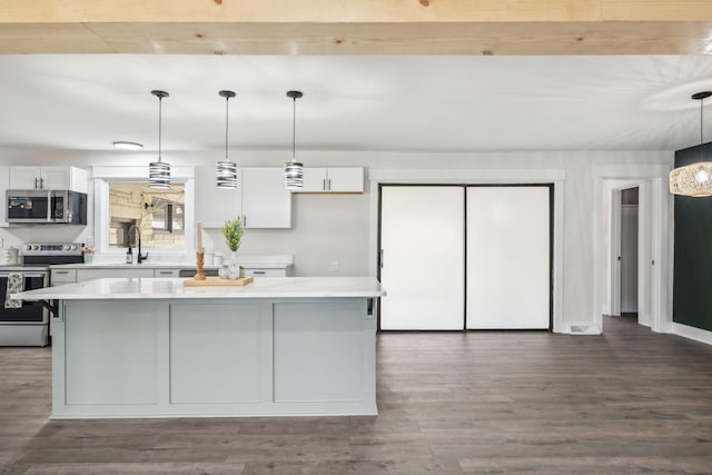 kitchen with a kitchen island, dark wood-type flooring, stainless steel appliances, light countertops, and white cabinetry