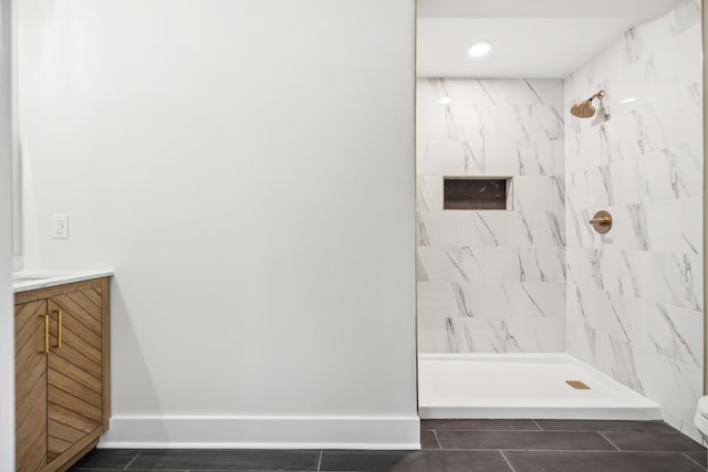 bathroom featuring tiled shower, vanity, and baseboards