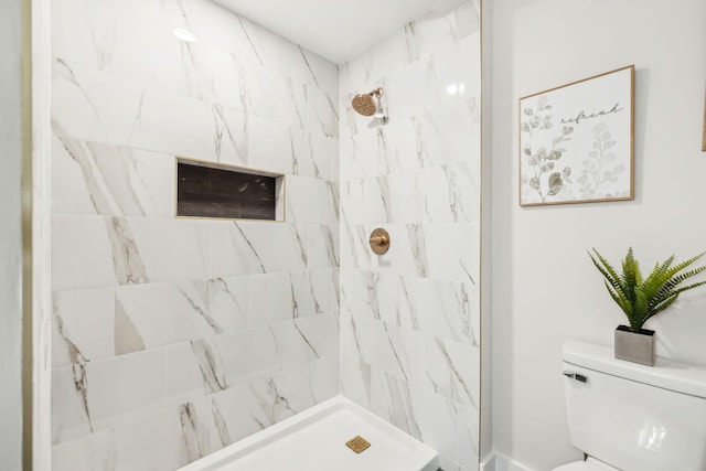 bathroom with a tile shower and toilet