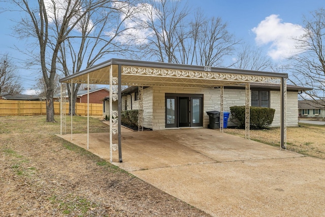 exterior space with concrete driveway, a carport, and fence