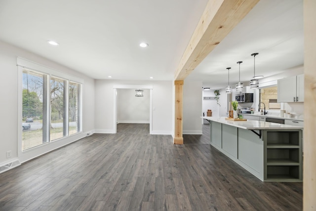 unfurnished living room with dark wood-style floors, baseboards, visible vents, and a sink